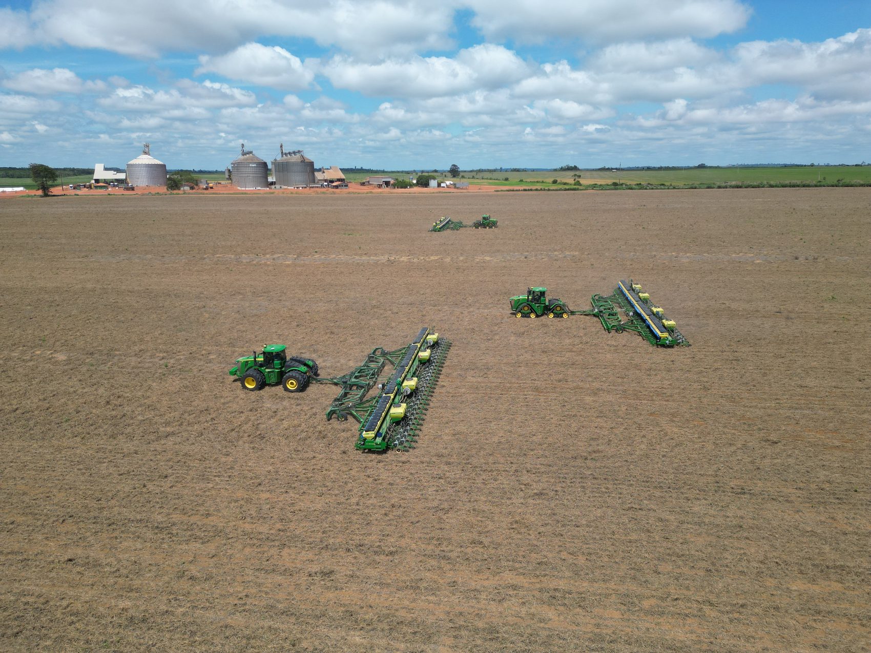 Plantio mecanizado com plantadeiras e silos ao fundo